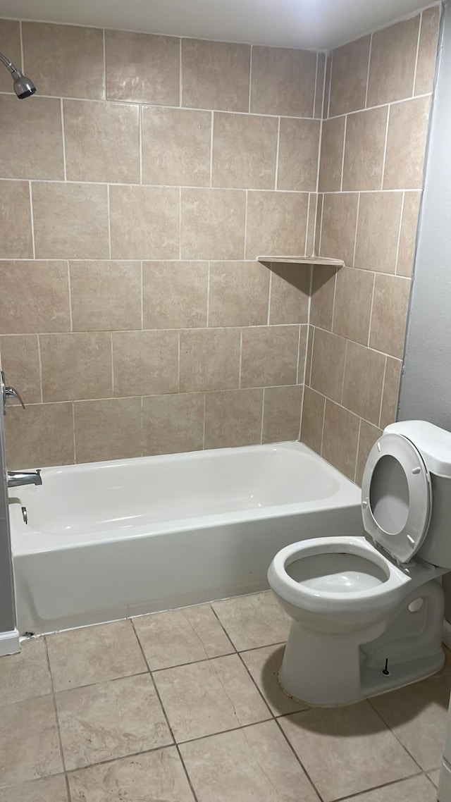 bathroom with toilet, tiled shower / bath, and tile patterned floors