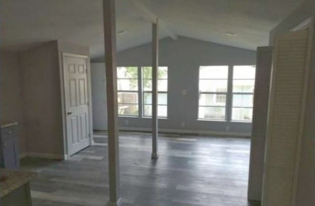 unfurnished living room with dark wood-type flooring and vaulted ceiling with beams