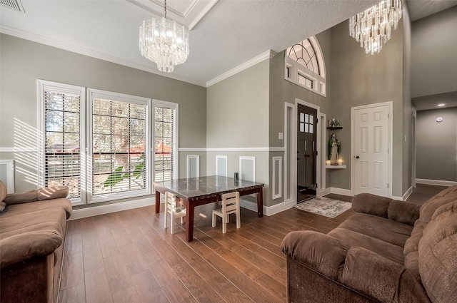 interior space featuring a towering ceiling, an inviting chandelier, ornamental molding, and wood-type flooring