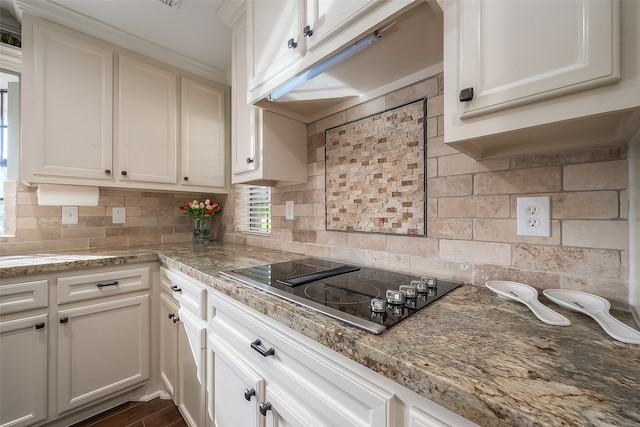 kitchen featuring light stone countertops, tasteful backsplash, white cabinets, and black electric cooktop