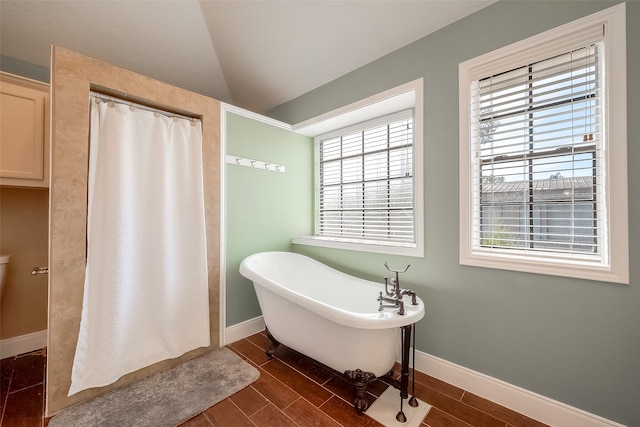 bathroom featuring lofted ceiling, hardwood / wood-style floors, and a tub