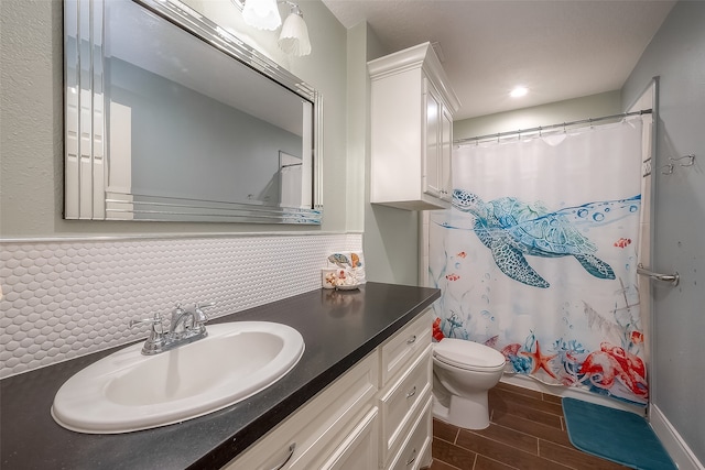 bathroom with decorative backsplash, hardwood / wood-style floors, toilet, vanity, and curtained shower