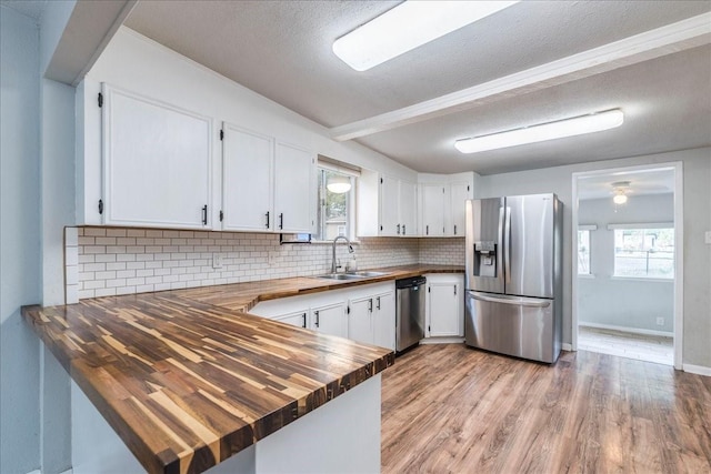 kitchen featuring wooden counters, stainless steel appliances, sink, light hardwood / wood-style flooring, and white cabinetry