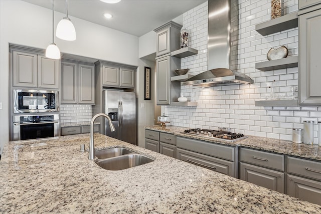 kitchen featuring gray cabinetry, tasteful backsplash, appliances with stainless steel finishes, wall chimney exhaust hood, and pendant lighting