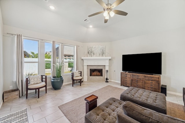 living room with a tiled fireplace, ceiling fan, lofted ceiling, and light tile patterned floors