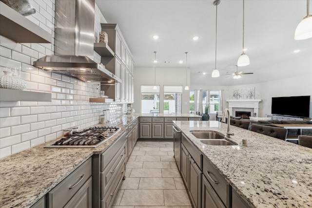 kitchen with wall chimney exhaust hood, sink, pendant lighting, and tasteful backsplash