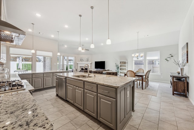 kitchen featuring an island with sink, stainless steel appliances, sink, light stone countertops, and pendant lighting