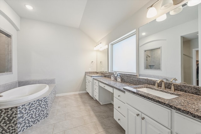 bathroom featuring vanity, vaulted ceiling, tiled tub, and tile patterned flooring