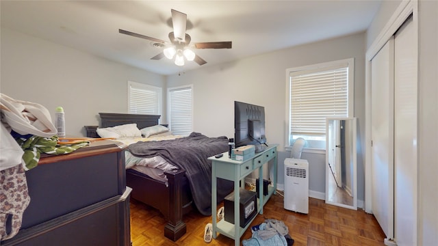 bedroom featuring multiple windows, dark parquet flooring, and ceiling fan