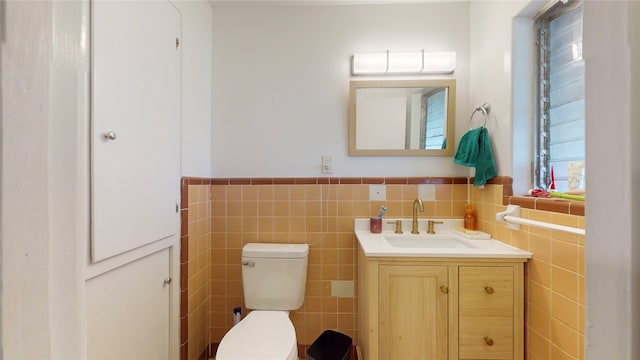 bathroom with vanity, toilet, and tile walls