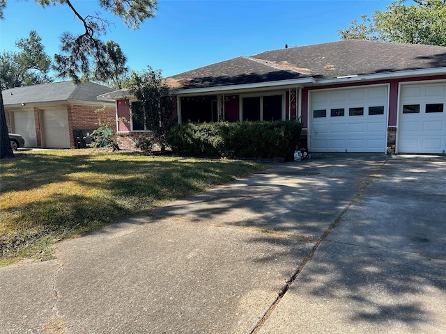 ranch-style home with roof with shingles, an attached garage, a front lawn, brick siding, and concrete driveway