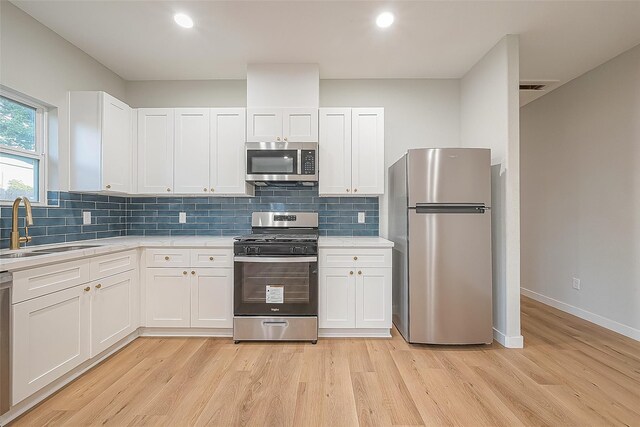 kitchen featuring sink, appliances with stainless steel finishes, white cabinets, and light hardwood / wood-style floors