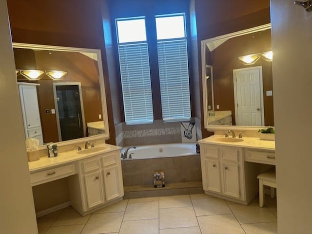full bath featuring a bath, a sink, tile patterned floors, and two vanities