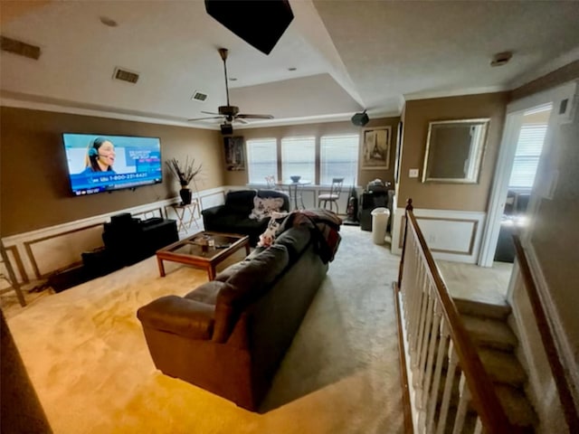 living room featuring a decorative wall, ornamental molding, carpet flooring, and visible vents