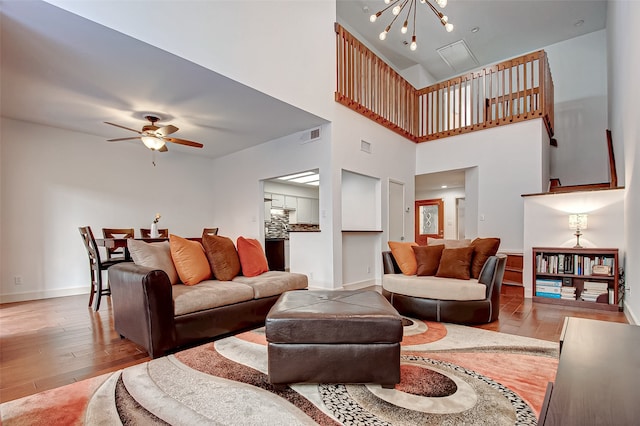 living room featuring ceiling fan, light hardwood / wood-style flooring, and a high ceiling