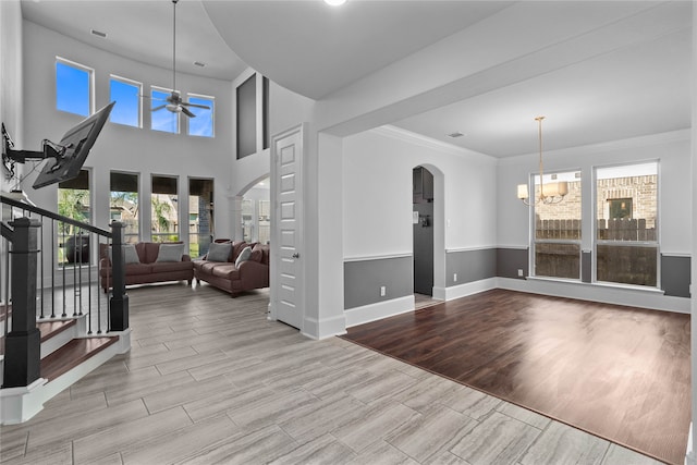 entryway with a wealth of natural light, crown molding, ceiling fan with notable chandelier, and light hardwood / wood-style floors