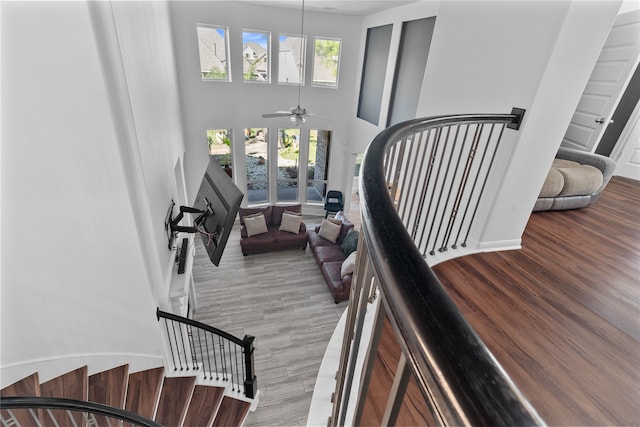 staircase featuring hardwood / wood-style floors, french doors, a towering ceiling, and ceiling fan