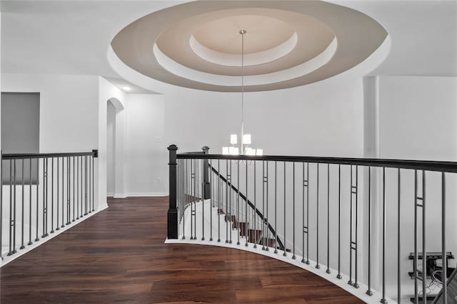 hallway featuring a notable chandelier, dark hardwood / wood-style floors, and a tray ceiling