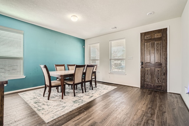 dining room featuring a textured ceiling and dark hardwood / wood-style floors