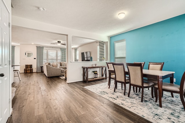 dining space featuring ceiling fan, wood-type flooring, and a textured ceiling