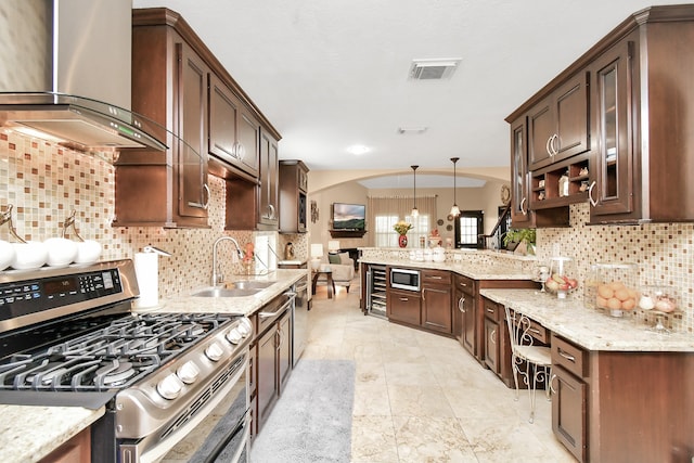 kitchen featuring tasteful backsplash, wall chimney range hood, appliances with stainless steel finishes, and pendant lighting