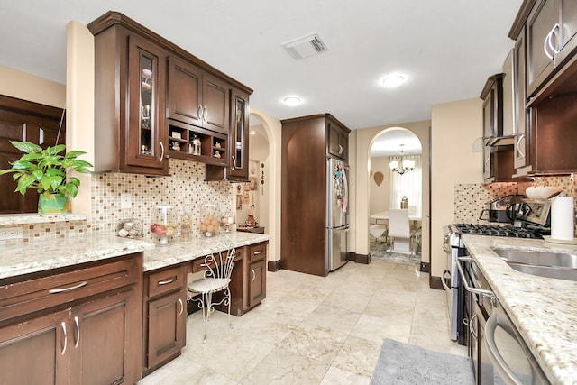 kitchen with light stone countertops, tasteful backsplash, appliances with stainless steel finishes, and dark brown cabinetry