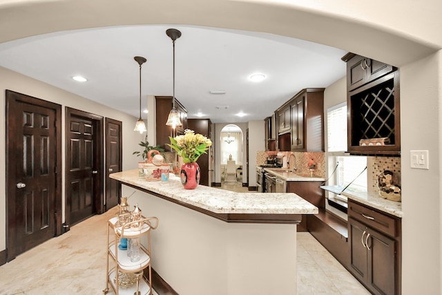 kitchen featuring a center island, dark brown cabinetry, decorative light fixtures, stainless steel range oven, and tasteful backsplash