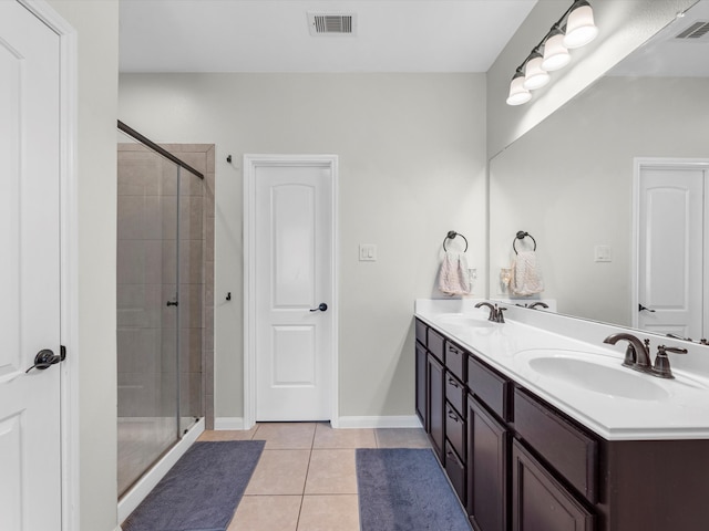 bathroom with a shower with door, vanity, and tile patterned flooring