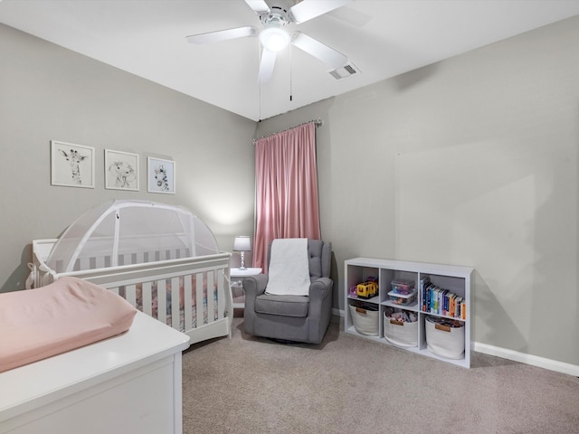 carpeted bedroom with ceiling fan and a crib