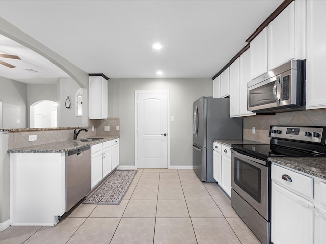 kitchen featuring appliances with stainless steel finishes, white cabinetry, and dark stone counters