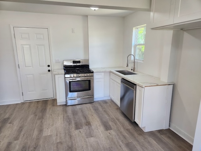 kitchen featuring light stone countertops, sink, light hardwood / wood-style floors, stainless steel appliances, and white cabinets