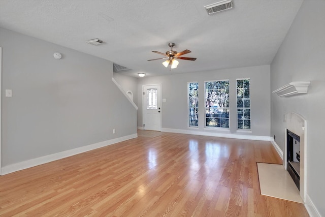 unfurnished living room with ceiling fan, light hardwood / wood-style floors, and a textured ceiling