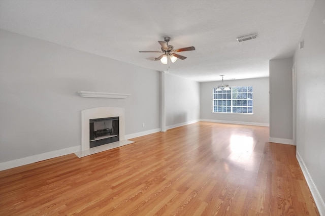 unfurnished living room featuring ceiling fan with notable chandelier and light hardwood / wood-style floors