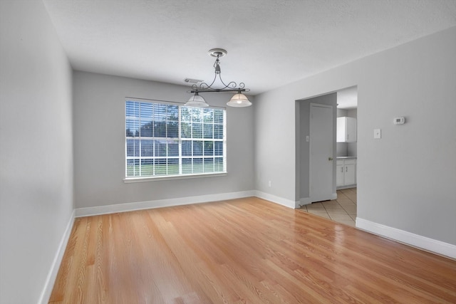 unfurnished room with a textured ceiling and light hardwood / wood-style flooring