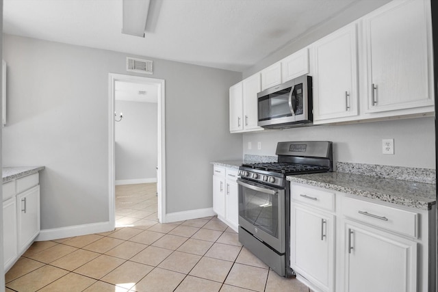 kitchen with white cabinets, light stone countertops, light tile patterned floors, and appliances with stainless steel finishes