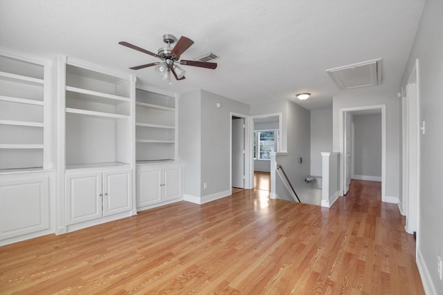 unfurnished living room with light wood-type flooring, built in features, and ceiling fan