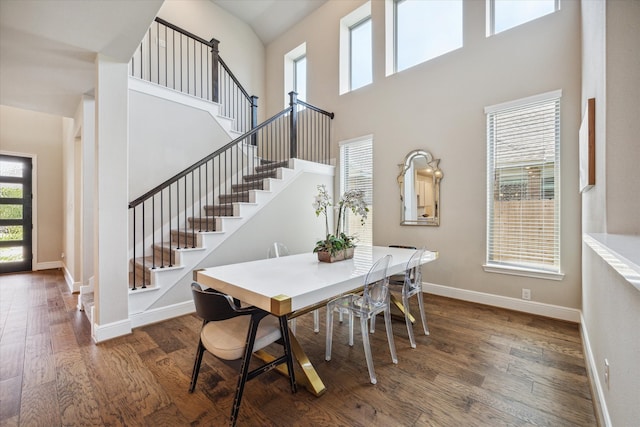 dining area with a towering ceiling and dark wood-type flooring