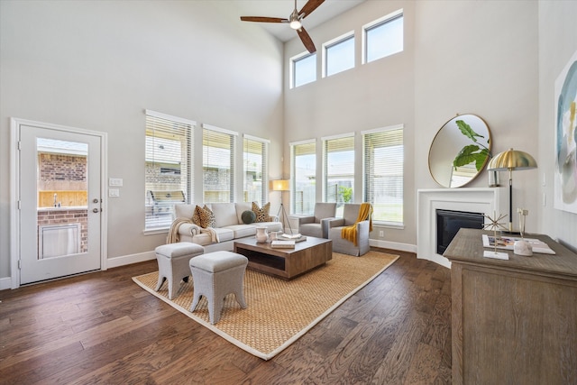 living room with ceiling fan, a healthy amount of sunlight, a high ceiling, and dark hardwood / wood-style floors