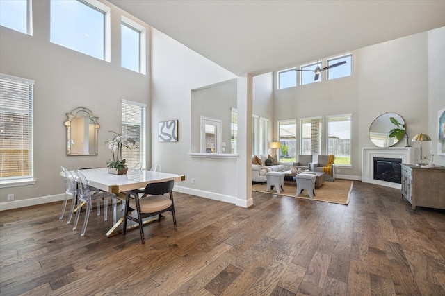 dining area featuring ceiling fan, a towering ceiling, and dark hardwood / wood-style flooring