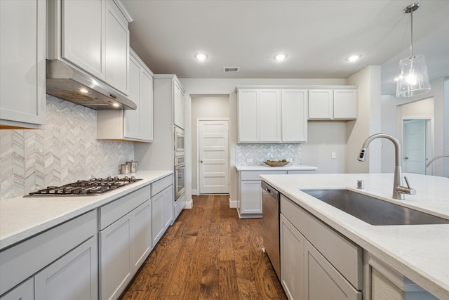 kitchen with decorative backsplash, hanging light fixtures, dark wood-type flooring, sink, and stainless steel appliances