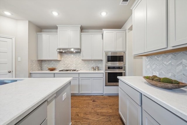 kitchen with decorative backsplash, white cabinets, stainless steel appliances, and dark hardwood / wood-style flooring