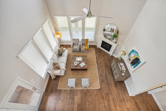 living room with dark wood-type flooring, a high ceiling, and ceiling fan