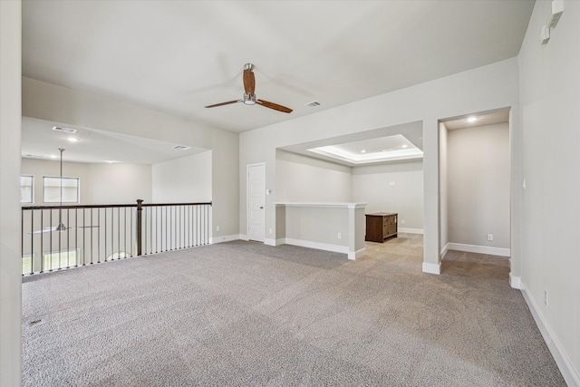 carpeted empty room featuring a raised ceiling and ceiling fan