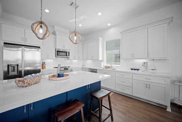 kitchen with stainless steel appliances, decorative light fixtures, a kitchen bar, and white cabinets