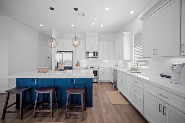 22831 Cuadro St, Galveston, TX 77554 - kitchen with stainless steel appliances, a sink, a breakfast bar area, a center island, and white cabinets