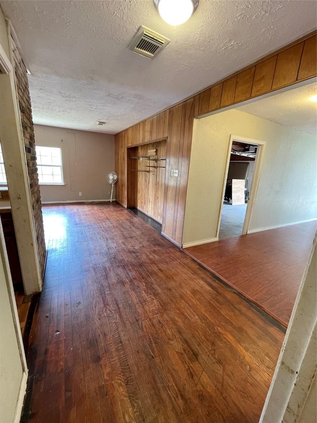 spare room with wooden walls, dark hardwood / wood-style flooring, and a textured ceiling