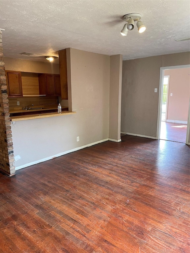 unfurnished living room with dark hardwood / wood-style floors and a textured ceiling