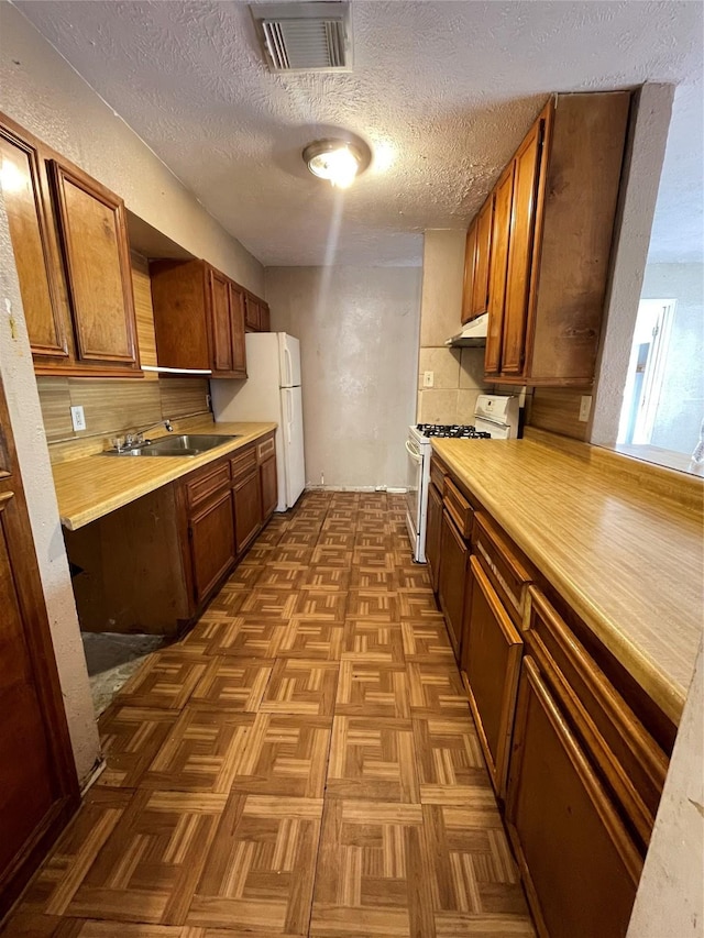 kitchen featuring white appliances, dark parquet floors, sink, a textured ceiling, and tasteful backsplash