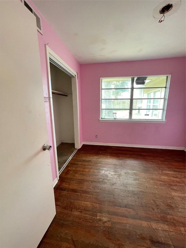 unfurnished bedroom with dark hardwood / wood-style flooring and a closet