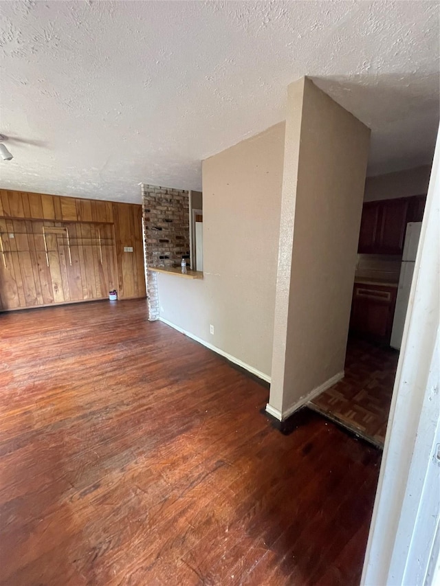 unfurnished living room featuring dark hardwood / wood-style flooring and a textured ceiling